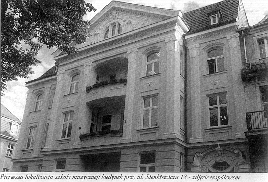 Widok kamienicy w stylu klasycystycznym. Podpis: "Pierwsza lokacja szkoły - budynek przy ulicy Sienkiewicza 18 - zdjęcie współczesne